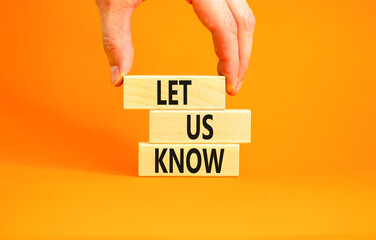 Let us know symbol. Concept words Let us know on wooden blocks on a beautiful orange table orange background. Businessman hand. Business and let us know concept. Copy space.