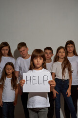 Girl hold placard with 'Help' word near children