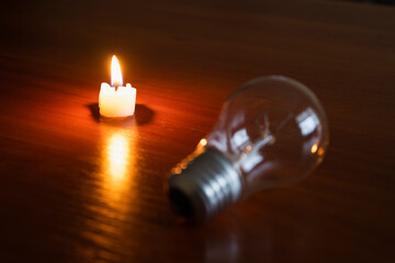 light bulb and candle on black background, blackout	