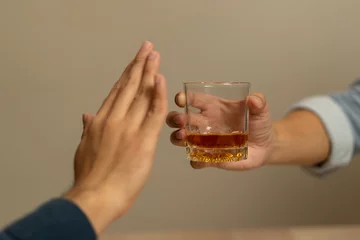 Foto op Canvas Alcoholism, sad depressed asian young man, male hand holding glass, refuse alcoholic beverage, drink whiskey at night. Treatment of alcohol addiction, having suffered abuse problem alcoholism concept. © KMPZZZ