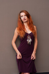 Portrait of lovely slim redhead girl in wine dress and dreamcatcher craft talisman
