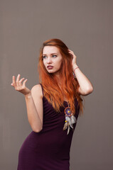 Fototapeta premium Portrait of lovely slim redhead girl in wine dress and dreamcatcher craft talisman