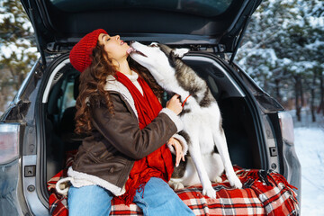 Young woman and cute husky dog enjoying and have fun winter holidays among snowy landace. Travel concept. Winter season.
