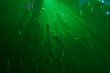Silhoutte of concert crowd having fun. Group of young people partying on rave in night club - obrazy, fototapety, plakaty