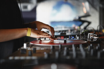 Fototapeta na wymiar Female DJ plays set with vinyl record player and sound mixer. Professional club disc jockey mixing musical tracks on stage