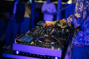 Party DJ mixing techno music with modern CD turntables and four channel sound mixer. Club disc...
