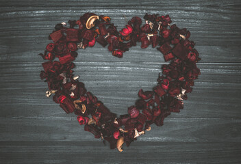 Wooden background with composition of leaves and red dry flowers in the shape of a heart