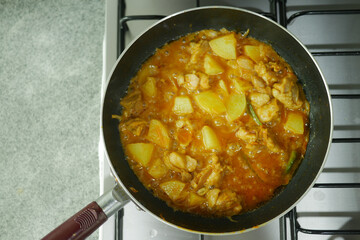 cooking chicken curry in a cooking pan 