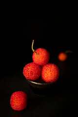 Arbutus, the fruit of the strawberry tree, with a black background and with copy space. Ripe wild berries with rough texture