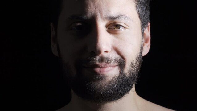 Depressed man on black background.
Mentally ill man with psychological problems smiling looking at camera.
