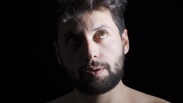 Mentally ill man on black background, mental disorders and hallucinations.
Man looking at camera is crazy, mentally ill man with psychological problems.

