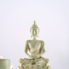 Buddhism composition with white Buddha statue and candles on a light gradient background. Vesak, Buddha Day. Mental health, relax, yoga and meditation. Soft image style. Front view