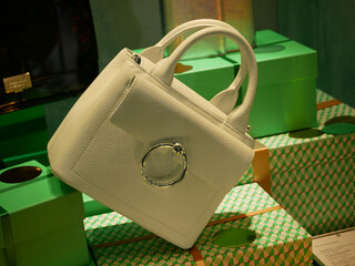 Idée de cadeau : Sac à main en cuir  blanc pour femme dans une vitrine de Noël d'un grand magasin. Paquets cadeaux verts.