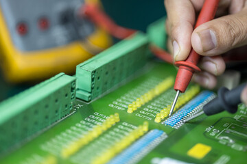 Professional hand measuring resistor on electronic circuit board