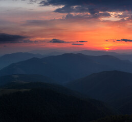 Beautiful panoramic sunset in the mountains landscape. Dramatic evening sky. Green hills covered by forest. 