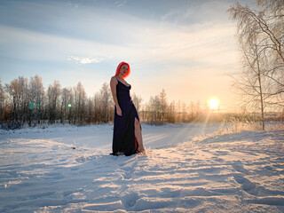 A beautiful woman with pink hair in a formal dress walks barefoot in the snow. Hardening on the...