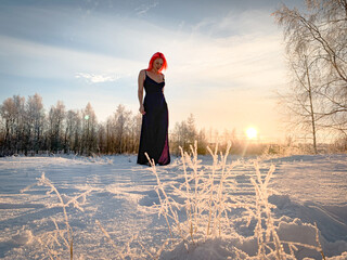 A beautiful woman with pink hair in a formal dress walks barefoot in the snow. Hardening on the street, frost in Siberia, winter swimming. Good health, cold therapy