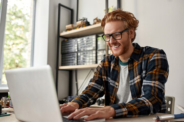 Smiling male IT engineer typing or watching laptop