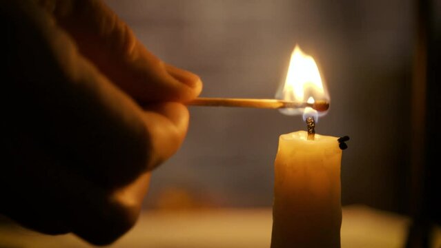 closeup man lighting a candle with a match