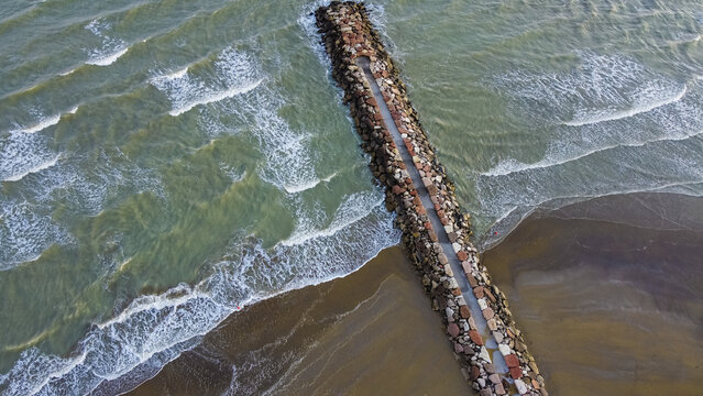 Aerial shot of Eraclea beach with sand, waves and stones, Veneto