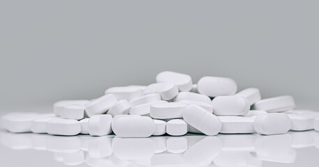 Medical background of many capsule tablets or pills on white table. Close up. Healthcare pharmacy and medicine concept with copy space Painkillers or prescription drugs consumption. Banner