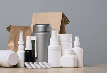Online pharmacy. prescription drugs and over the counter medication ready for delivery to customers. Pills and spray white mockup containers and buff paper bags on table. Drugstore shopping