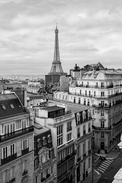 A black and white view over the rooftops of Paris with the Eiffel Tower in the background.