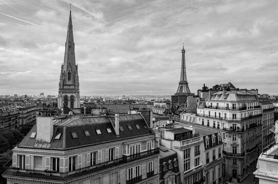 A black and white view over the rooftops of Paris with the Eiffel Tower in the background.