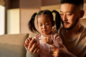 Father and daughter checking temperature at home