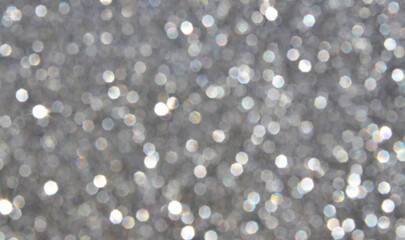 Blurred glitter background in silver colour as a part of Christmas design.Holiday abstract texture with bokeh lights.Fabric sequins.Selective focus. 