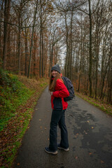 young tourist woman with backpack in an autumnal forest. A single independent courageous and happy woman.