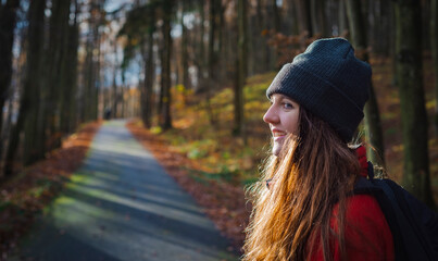 young tourist woman on a trail in an autumnal forest. A single independent courageous and happy woman.