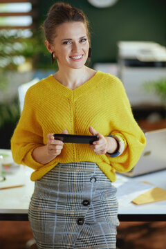 happy trendy business owner woman in sweater in green office