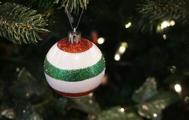 Weihnachtsdekoration mit grün-rot-weißer Weihnachtskugel am Weihnachtsbaum hängend 
