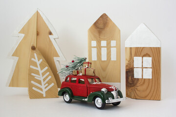 Red car with a Christmas tree and gift boxes and wooden toys in the Scandinavian style