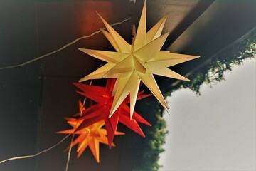 Weihnachtsdekoration mit weißem, rotem und gelbem Stern unter Decke von Holzhütte auf...