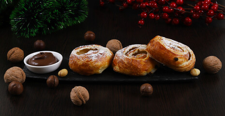 Puff rolls with raisins and chocolate cream in a white plate on the Christmas table, New Year....