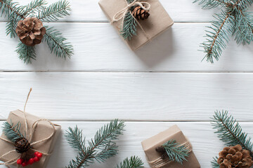 Christmas background with eco-packed gifts, blue fir branches on a white wooden background.