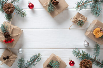 A Christmas gift wrapped in kraft paper and decorated with natural materials, on a white wooden table.