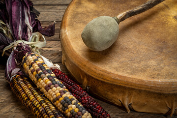 handmade, native American style, shaman frame drum covered by goat skin with a beater or a rustic wood with ornamental corn