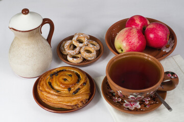 a cup of tea with a bun and apples for breakfast