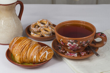 a cup of tea with a croissant on the table with a white tablecloth