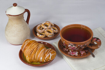 a cup of tea with a croissant on the table with a white tablecloth