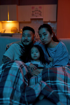 Asian Family Watching TV Or Movie On Sofa At Home