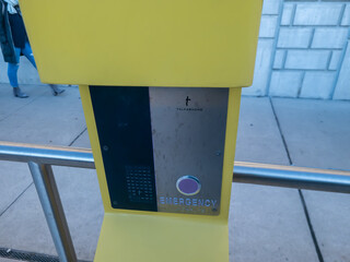 A close-up of the call button on a yellow Emergency  Call tower at the Ferry Street Q- line station...