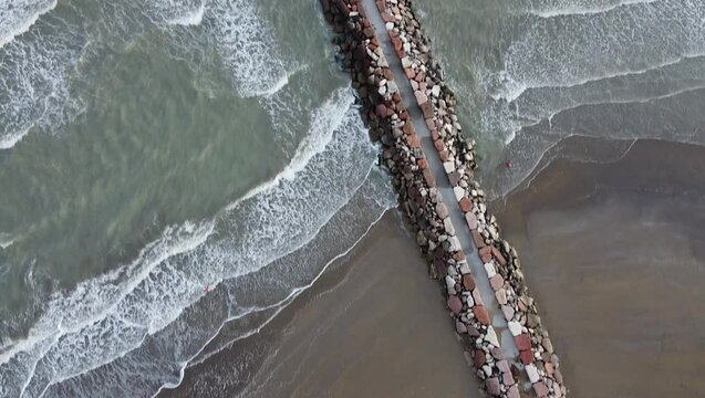 Aerial shot of Eraclea beach with sand, waves and stones, Veneto