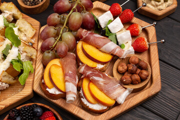 A dish with appetizers of cheese, fruits, vegetables, crackers, meat, berries and nuts