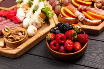 A dish with appetizers of cheese, fruits, vegetables, crackers, meat, berries and nuts