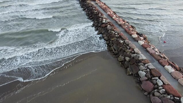 Aerial shot of Eraclea beach with sand, waves and stones, Veneto