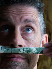 Finance man's money moustache, close up. A playful shot with an old English one pound note. Staring...